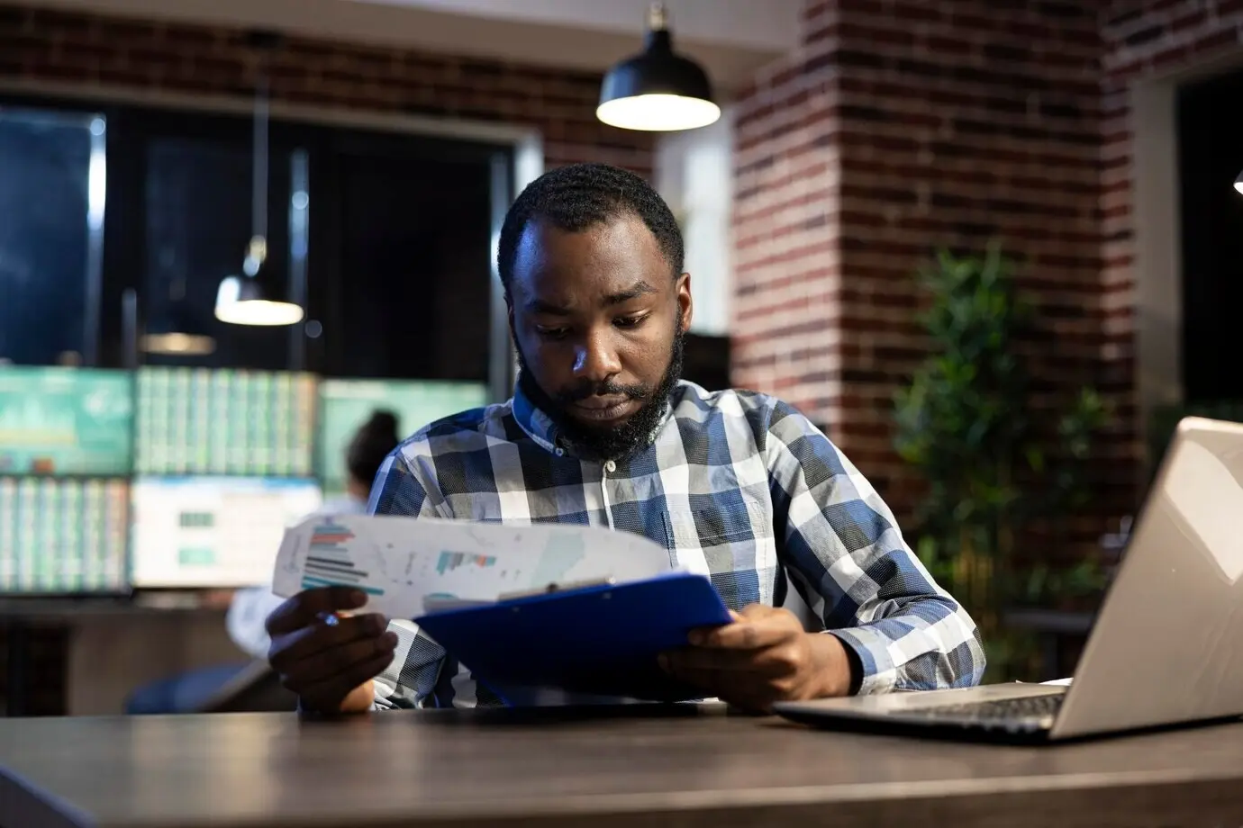 Сосредоточенный мужчина просматривает данные на планшете с зажимом.